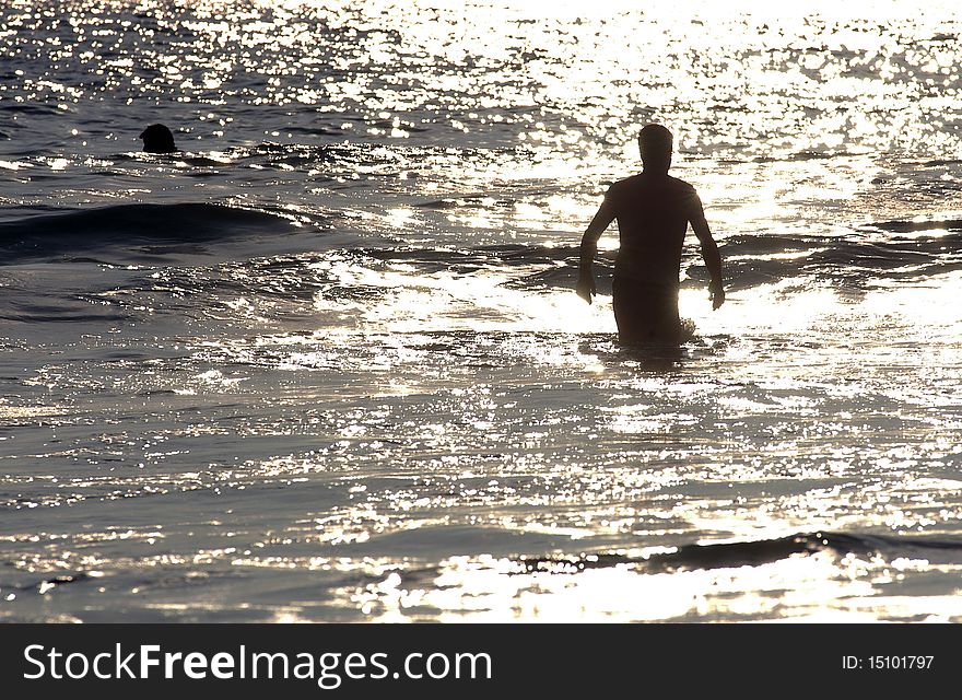 Silhouette of  man comming out of sea  during sunset