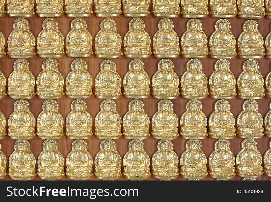 Pattern of gold buddha doll on the hard wood.