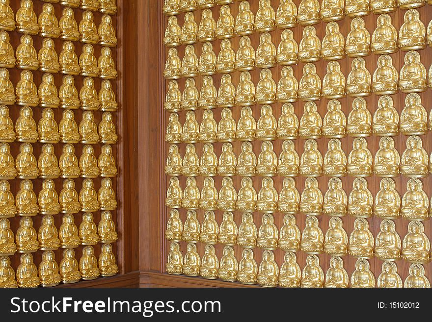 Pattern of gold buddha doll on the hard wood.