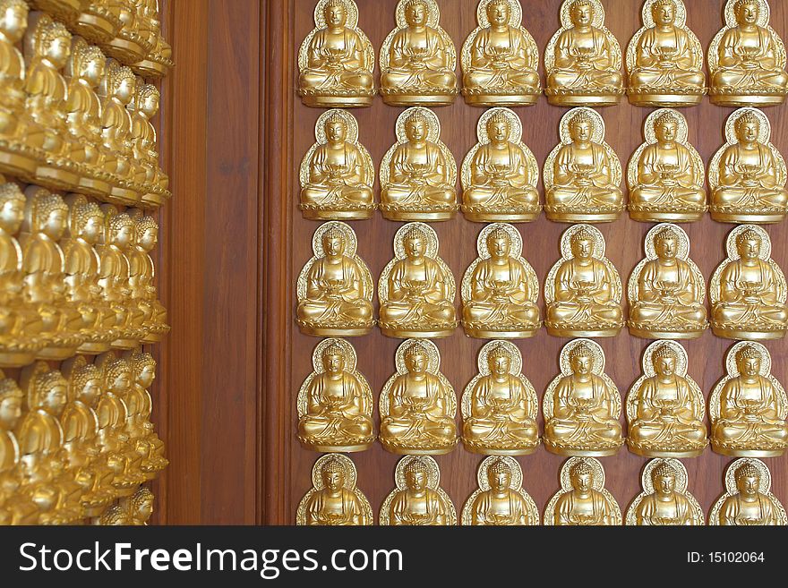 Pattern of gold buddha doll on the hard wood.