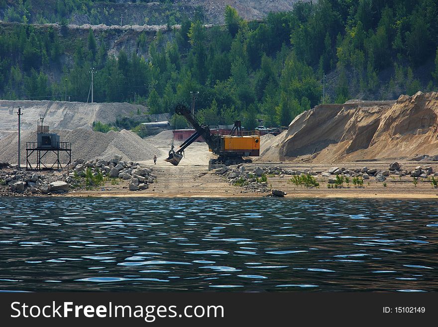 Stone mining with big tractor on a river coast