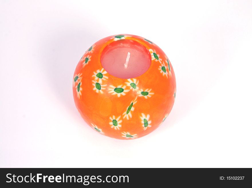 Spherical unlit orange candle with flower design