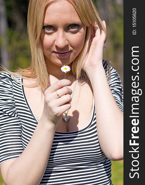 Blond girl holding and smelling Daisy flower