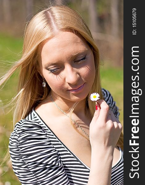 Blond girl holding and smelling Daisy flower