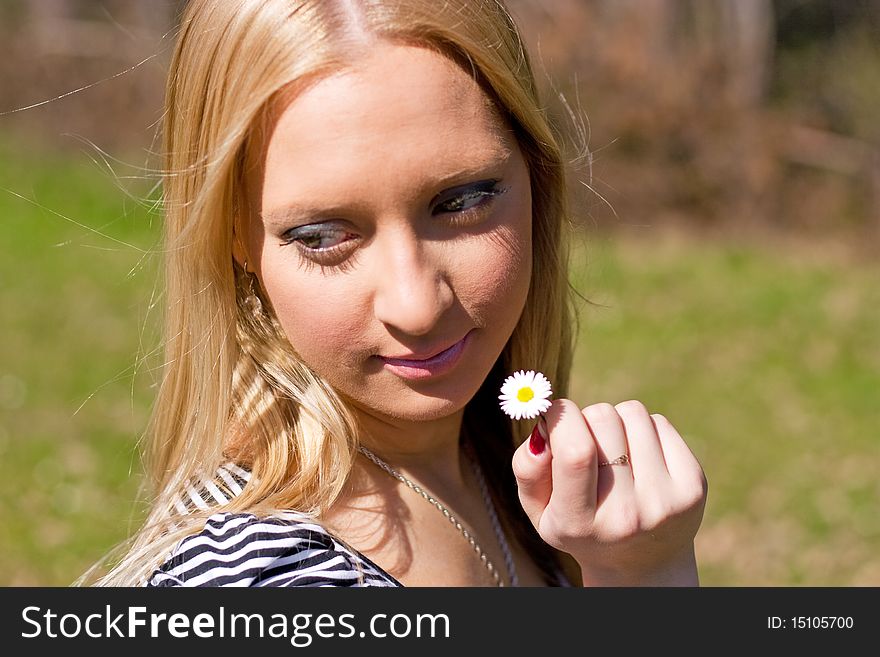 Blond girl holding and smelling Daisy flower