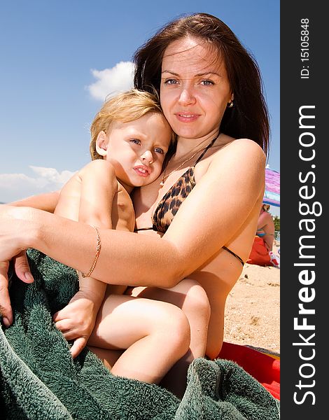 Young mother holding her little son in hands sitting on the beach. Young mother holding her little son in hands sitting on the beach