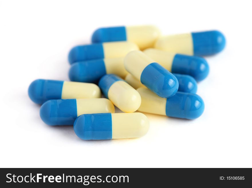 Close up of a pile of blue yellow pills isolated on white background