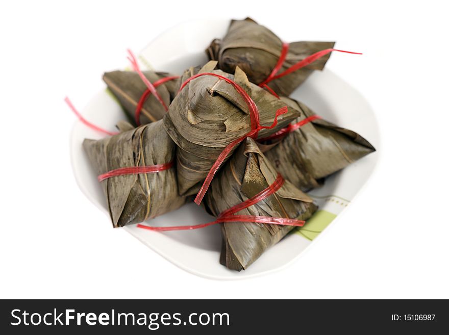 Close up of many rice dumplings on plate over white background.