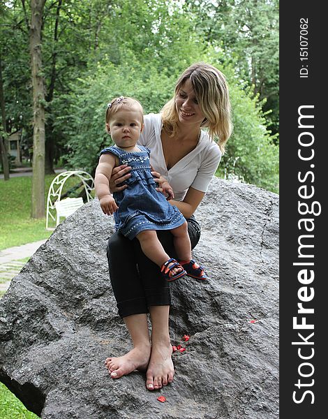 The mum with the daughter sit on a stone