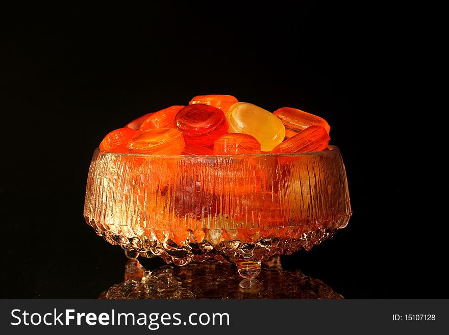 Sweets in a glass bowl with reflection and black background