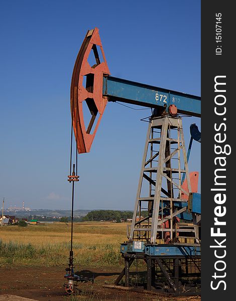 An oil pump jack on blue sky.