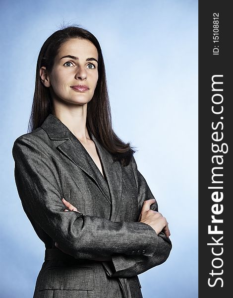 Half-body portrait of smiling confident businesswoman with entwined arms in grey suit looking up-right. Half-body portrait of smiling confident businesswoman with entwined arms in grey suit looking up-right.