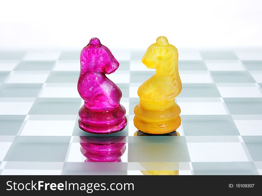 Two Knight chess pieces from opposite sides face off. Two Knight chess pieces from opposite sides face off.
