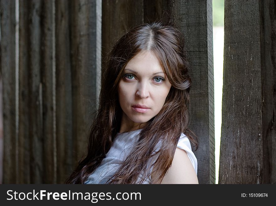 Close-up of beautiful woman against a old wooden wall. Close-up of beautiful woman against a old wooden wall