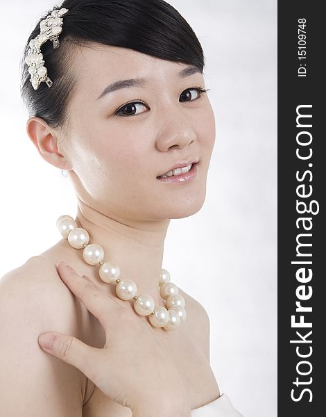 Beautiful bride with perfect natural makeup,smiling,headgear on head,wearing pearl necklace