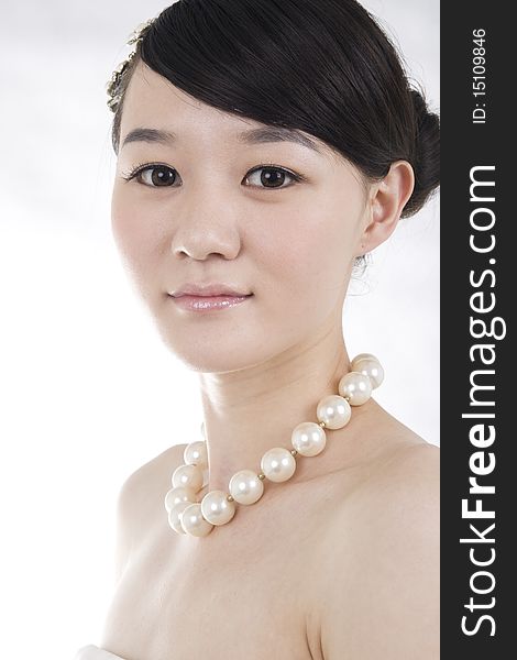 Beautiful bride with perfect natural makeup,smiling,headgear on head,wearing pearl necklace