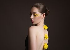 Young Woman Spa. Yellow Flowers Along Her Back, Face And Body In The Shade. Back View. Dark Background Stock Photo
