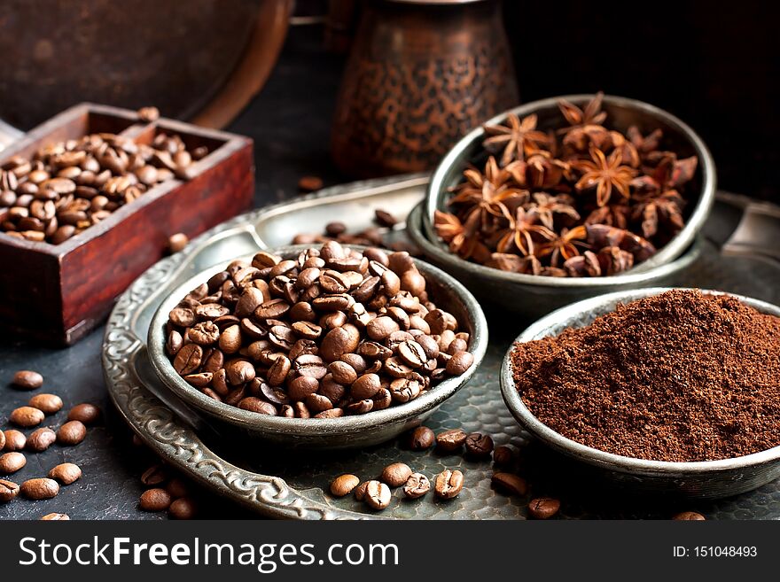 Food  background  with  black roasted coffee beans, ground coffee and anise in dishes, selective  focus with  shallow depth of field. Food  background  with  black roasted coffee beans, ground coffee and anise in dishes, selective  focus with  shallow depth of field