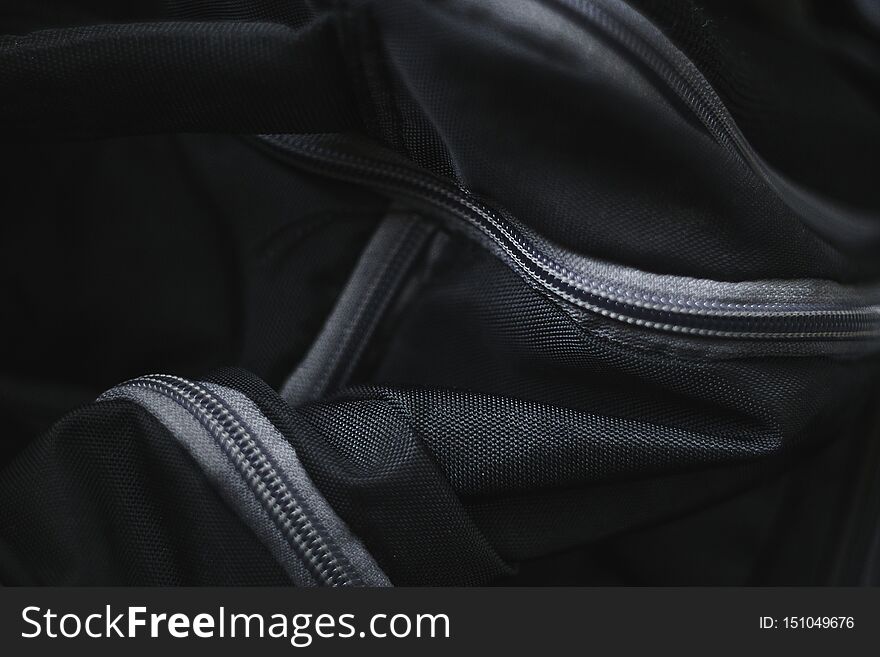 Abstract picture of black fabric travel bag with gray plastic zippers