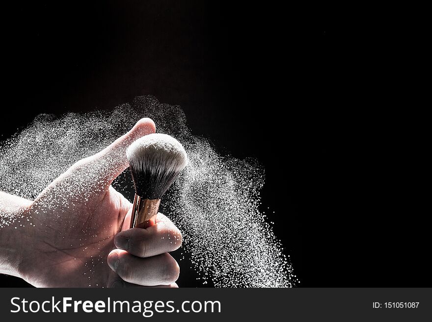 Thick Black Brush In Motion And Loose Powder Particles Scattered Around