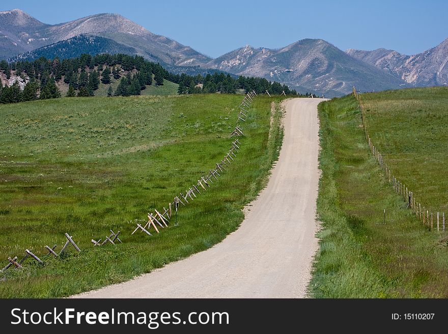 A dirt road and a wooden fence lead to the distant hills. A dirt road and a wooden fence lead to the distant hills.