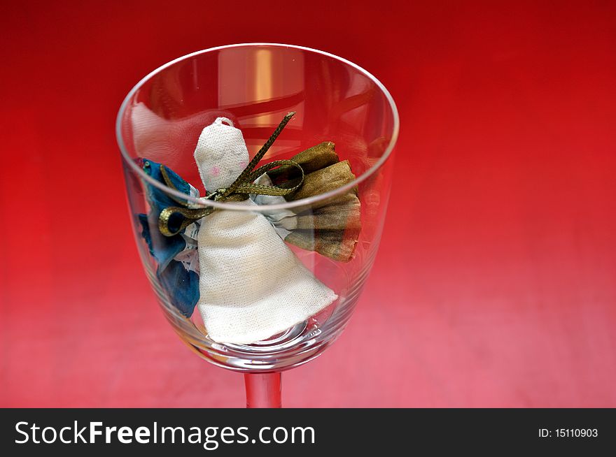 Pour feliciter (happy new year) - angel puppet in a glass on a red background. Pour feliciter (happy new year) - angel puppet in a glass on a red background