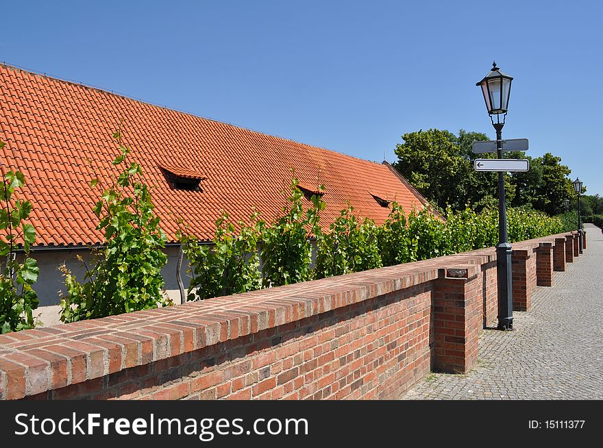 Nice orange roof over the brick wall with a blank signpost on the lamp. Nice orange roof over the brick wall with a blank signpost on the lamp