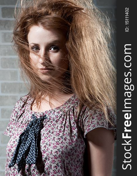 Redhaired mysterious woman against brick wall .