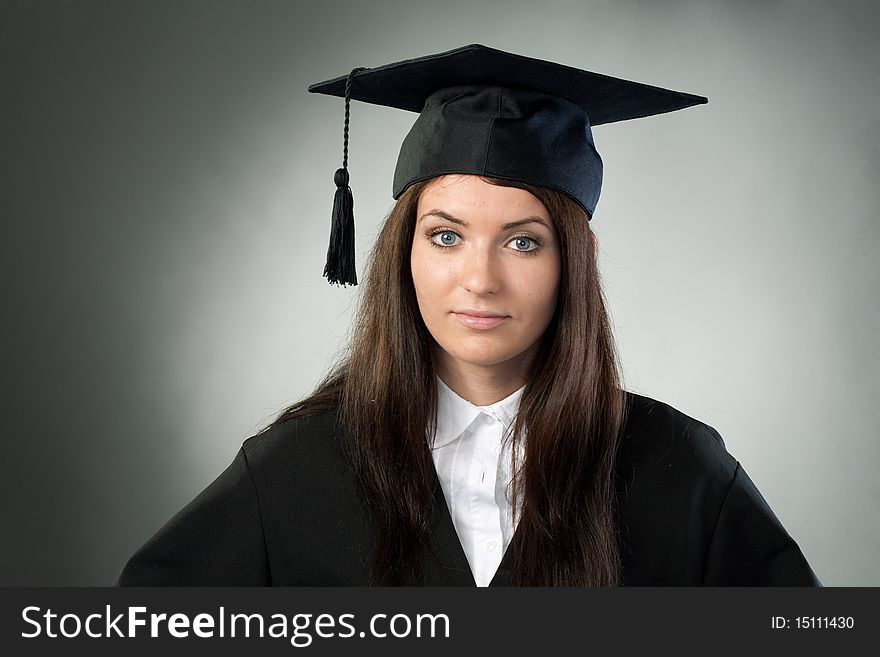 Young beauty graduate woman on gray background