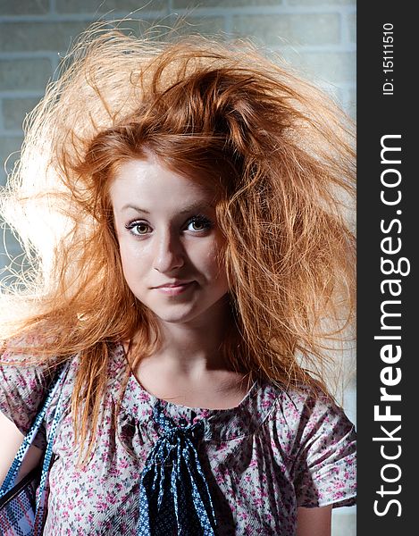 Redhaired mysterious woman against brick wall .