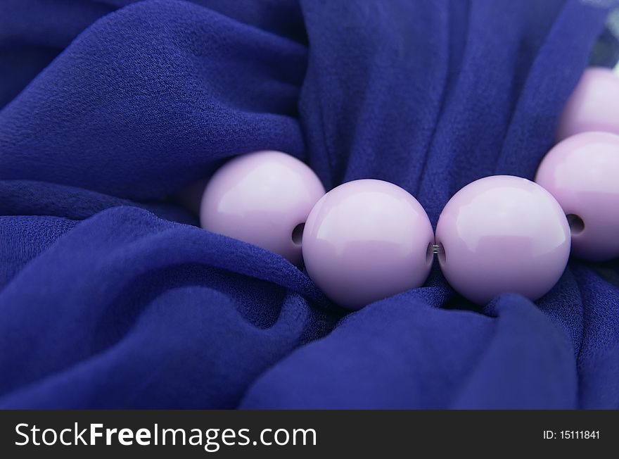 Lilac beads against dark blue scarf, close up. Lilac beads against dark blue scarf, close up