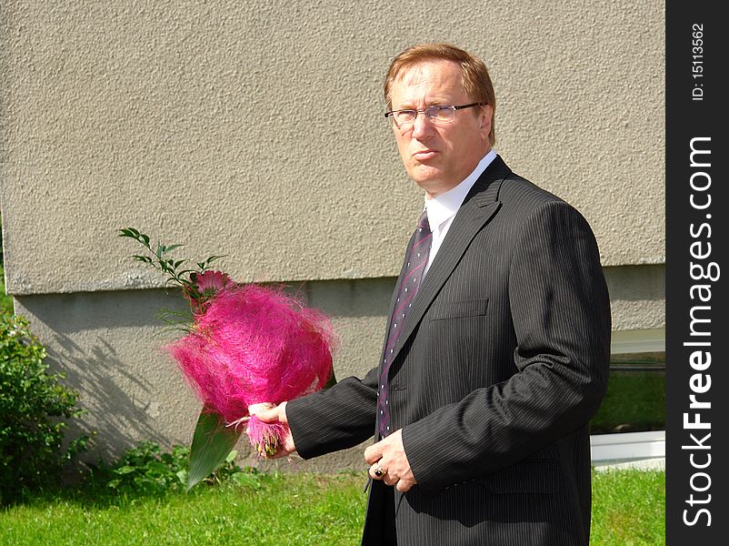 Portrait mature businessman with a bouquet of flowers near the office