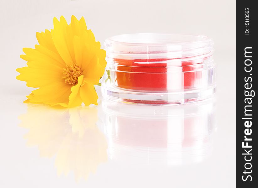 Jar of rouge with a yellow flower on white background. Jar of rouge with a yellow flower on white background