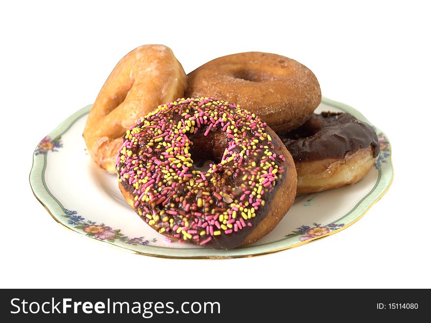 Assorted doughnuts, honey dipped, chocolate, sugar and sprinkled all arranged on a china dish.