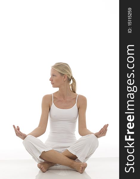 A young caucasian woman dressed in white sitting cross-legged doing yoga