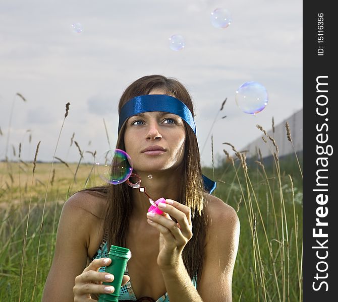 Thoughtful young woman blowing soap bubbles in summer day. Thoughtful young woman blowing soap bubbles in summer day