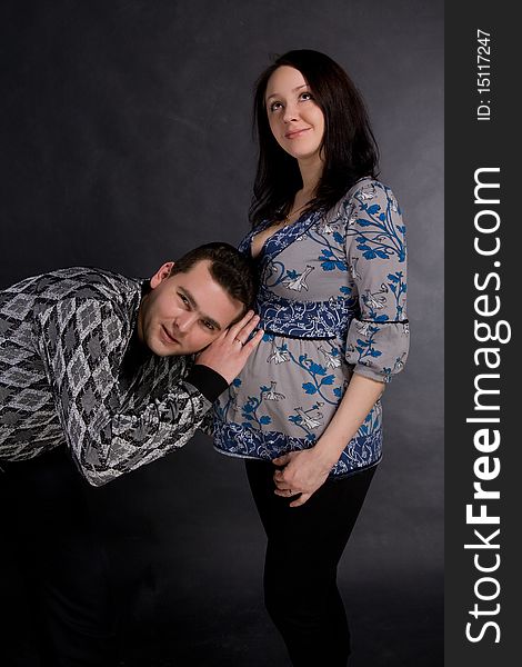 Pregnant couple posing, man has leant an ear to a stomach. Pregnant couple posing, man has leant an ear to a stomach