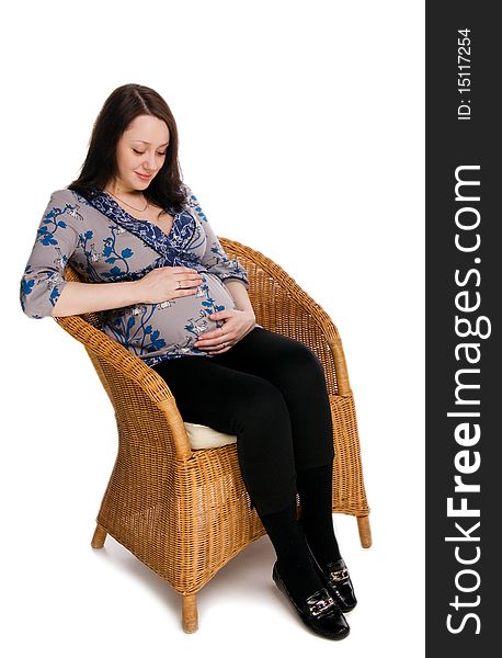 Pregnant woman sitting on a wicker chair and hugs belly, isolated on white. Pregnant woman sitting on a wicker chair and hugs belly, isolated on white