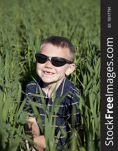 Boy with sunglasses in tall oat field