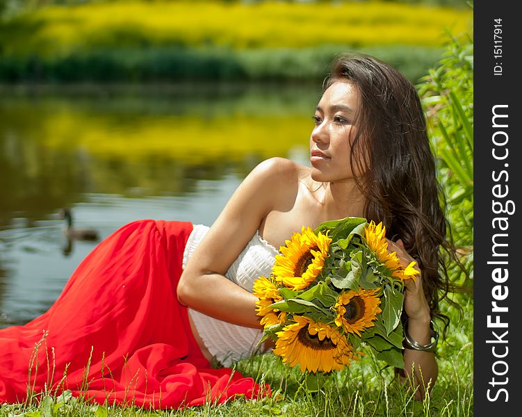 Young Asian woman with sunflowers in her hands. Young Asian woman with sunflowers in her hands.