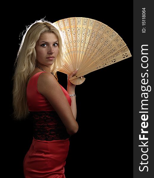 Blonde young lady in red dress with fan on black background. Blonde young lady in red dress with fan on black background