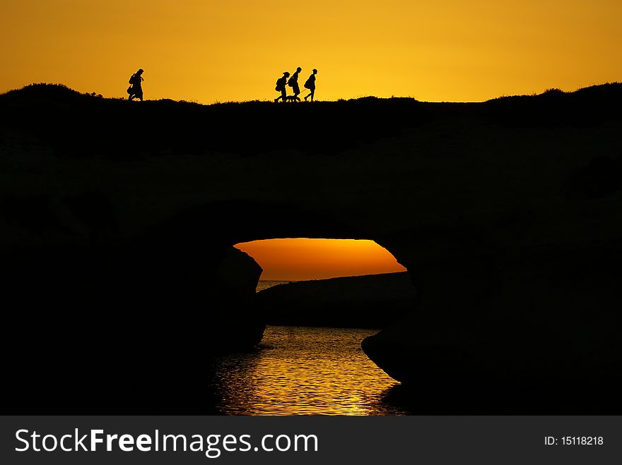 Silhouettes Of People Over The Sea In The Sunset