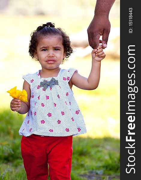 A very young african american (black) girl holds some flowers while wearing a white and red outfit. A very young african american (black) girl holds some flowers while wearing a white and red outfit.