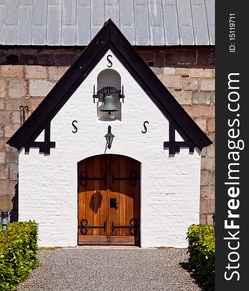 White gable from church entrance with beautiful door and church bell. White gable from church entrance with beautiful door and church bell.