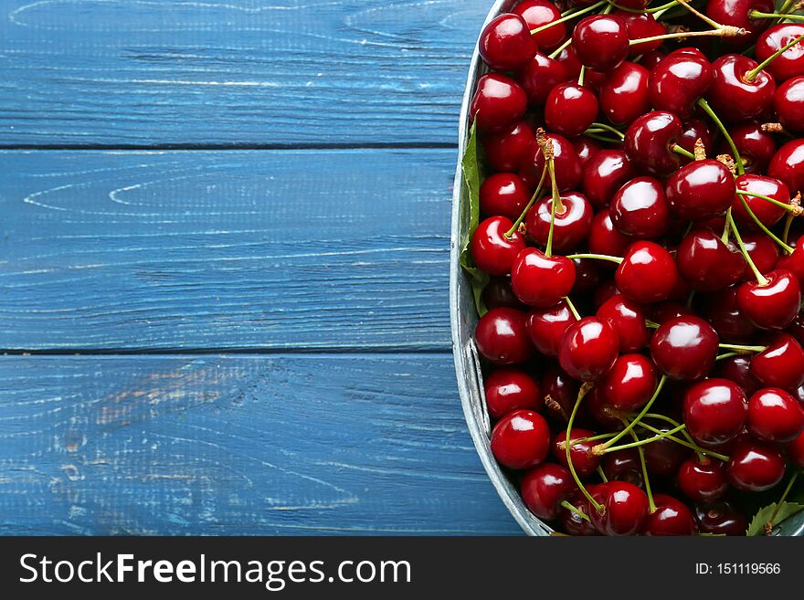Bowl with tasty cherries on wooden table, top view