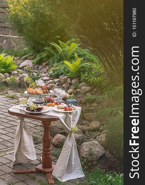 Table with festive treat and tablecloth in the summer garden