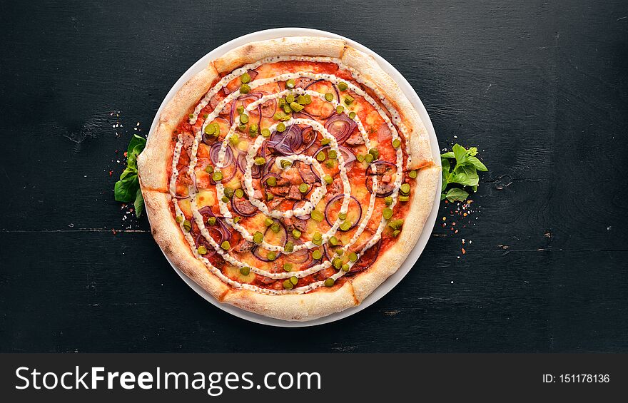 Pizza with onions, sausage and cucumber. On a wooden background. Top view. Free space for your text