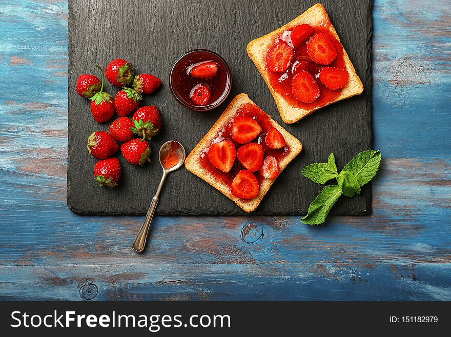 Slices of bread with delicious strawberry jam on wooden table
