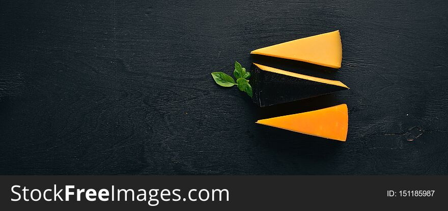 Assortment of hard cheeses. Top view. On a black wooden background. Free copy space