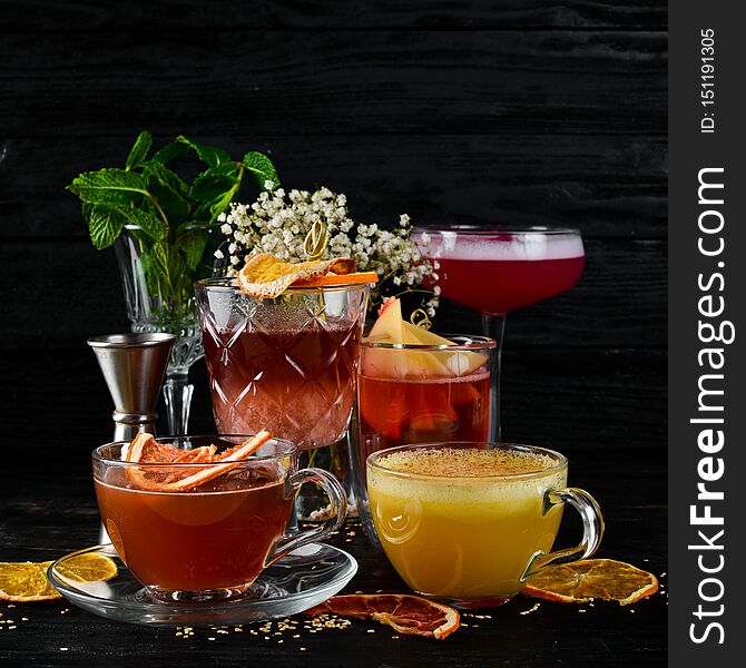 A selection of hot cocktails. Winter drinks. Hot wine. On a black wooden background. Top view. Free copy space